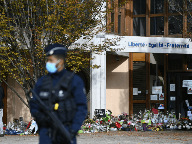 People look at flowers layed outside the Bois d'Aulne secondary school in homage to slain history teacher Samuel Paty, who was beheaded by an attacker for showing pupils cartoons of the Prophet Mohammed in his civics class, on October 19, 2020, in Conflans-Sainte-Honorine, northwest of Paris. - Paty, 47, was …