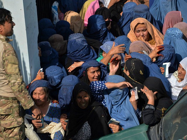 Women gather outside the main entrance gate of a football stadium following a stampede tha