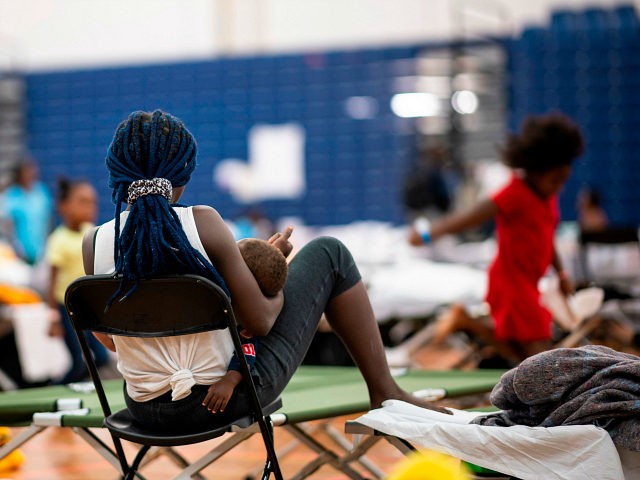 A migrant holds her baby at The Expo, a sports complex converted into an emergency shelter, on June 25, 2019 in Portland, Maine. - Converging from far flung corners of the earth, and operating by word of mouth and social media, hundreds of African migrants have turned this town into …