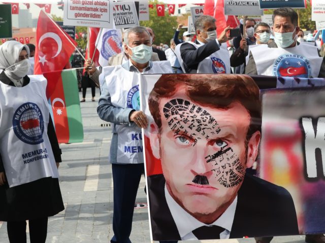 Men hold a sign bearing a picture of French President Emmanuel Macron with a shoe print on it as Turkish protesters shout slogans during a demonstration against French President's comments over Prophet Muhammad cartoons, in Ankara, on October 27, 2020. - Muslims across the world have reacted furiously to Macron's …