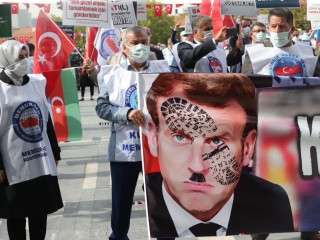 Men hold a sign bearing a picture of French President Emmanuel Macron with a shoe print on