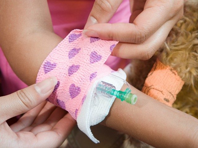 Girl having bandage put around catheter - stock photo