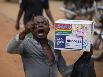 A man reacts while carrying a bag of noodles during a mass looting of a warehouse that have COVID-19 food palliatives that were not given during lockdown to relieve people of hunger, in Abuja, Nigeria, on October 26, 2020. - Nigeria, with 200 million inhabitants, counts the highest number of …