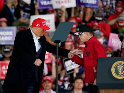 President Donald Trump greets former University of Iowa wrestling coach Dan Gable, right, during a campaign rally at Des Moines International Airport, Wednesday, Oct. 14, 2020, in Des Moines, Iowa. (AP Photo/Charlie Neibergall)
