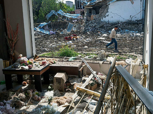 A man walks past a house destroyed by shelling by Azerbaijan's artillery during a military