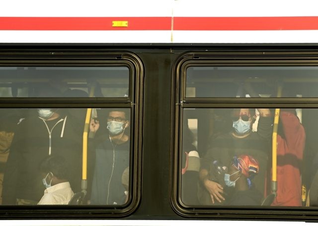 Commuters stand shoulder to shoulder inside a city bus while during rush hour in Toronto on Friday, Oct. 9, 2020. (Nathan Denette/The Canadian Press via AP)