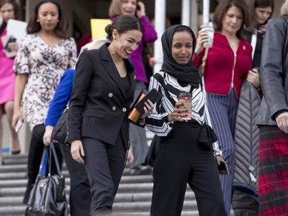 Rep. Alexandria Ocasio-Cortez, D-N.Y., center left, Rep. Ilhan Omar, D-Minn., center right, share a laugh as they walk down the House steps to take a group photograph of the House Democratic women members of the 116th Congress on the East Front Capitol Plaza on Capitol Hill in Washington, Friday, Jan. …