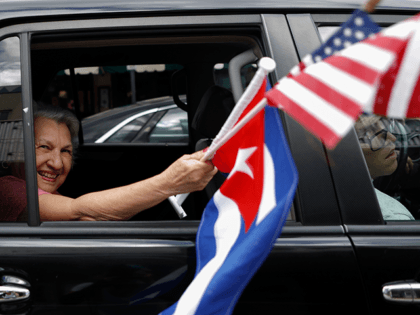 A woman waves American and Cuban flags as supporters of President Donald Trump drive in caravan down Calle Ocho in Little Havana, Miami, Saturday, Oct. 31, 2020. (AP Photo/Rebecca Blackwell)