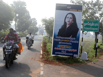 People ride past a billboard featuring U.S. democratic vice presidential candidate Sen. Kamala Harris at a crossing in Thulasendrapuram village, south of Chennai, Tamil Nadu state, India, Tuesday, Nov. 3, 2020. The lush green village is the hometown of Harris' maternal grandfather who migrated from there decades ago. Billboard in …