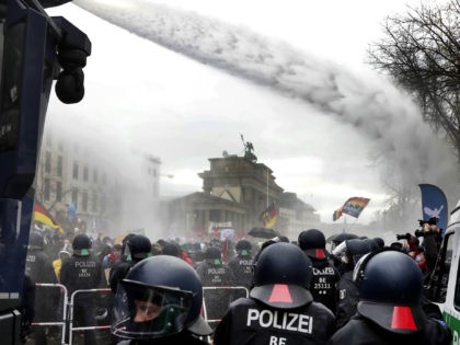 Police uses water canons to clear a blocked a road between the Brandenburg Gate and the Reichstag building, home of the German federal parliament, as people attend a protest rally in front of the Brandenburg Gate in Berlin, Germany, Wednesday, Nov. 18, 2020 against the coronavirus restrictions in Germany. Police …
