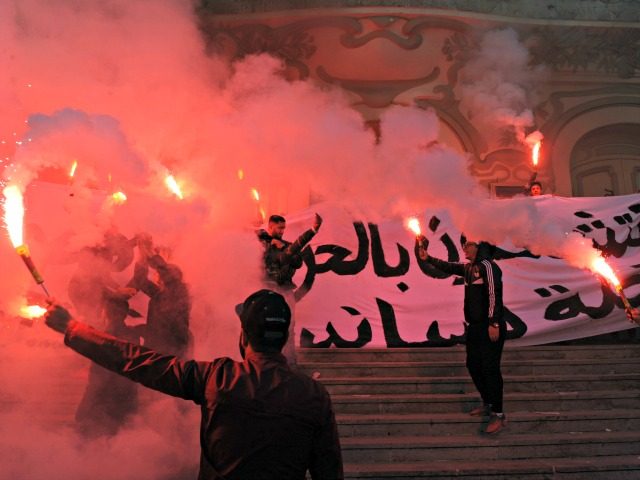 Tunisian protesters carry flares and shout slogans during celebrations in central Tunis on