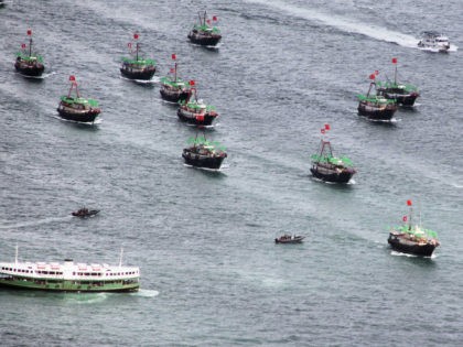 A flotilla of fishing boat bearing both the Chinese and Hong Kong flags sails past a Star Ferry (bottom-L) in Hong Kong on July 1, 2012 during celebrations to mark the 15th anniversary of the establishment of the Hong Kong Special Administrative Region (HKSAR). Hong Kong installed a new leader …