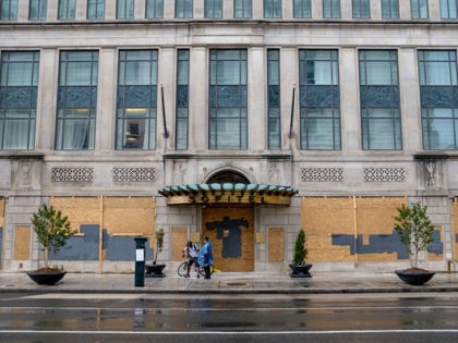 WASHINGTON, DC - June 20, 2020: People stand outside a boarded up and closed business near