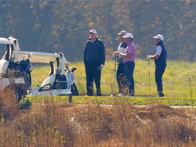 President Donald Trump, center standing, as he participates in a round of golf at the Trum
