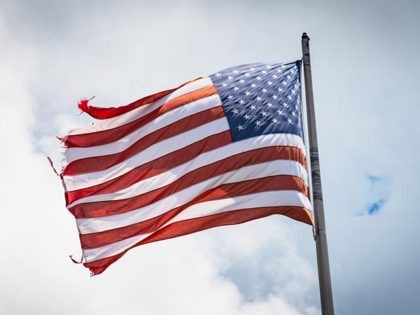 A visibly worn American flag waves in the wind.