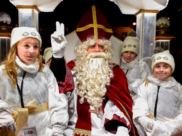 Saint Nicholas (2ndL) gestures from his float as he poses with children during the festivi