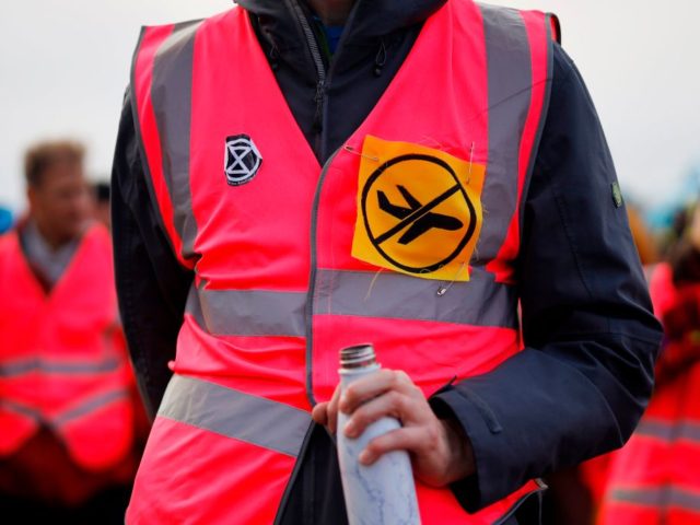 An activist from climate action group Extinction Rebellion wears a 'no planes' p