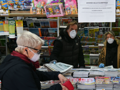 A resident wearing a protective mask (L) buys a newspaper at a newstand in Rome's Portuense district on March 12, 2020, as Italy shut all stores except for pharmacies and food shops in a desperate bid to halt the spread of a coronavirus that has killed 827 in the the …