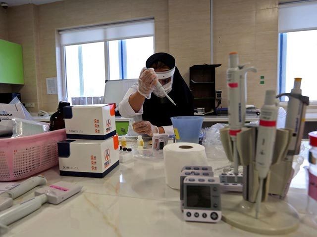 An Iranian member of the medical staff works on the production of COVID-19 test kits at a medical center in Karaj, at the northern Alborz Province, on April 11, 2020. - Iran reported 125 new deaths from the novel coronavirus, raising the overall toll in the Middle East's worst-hit country …