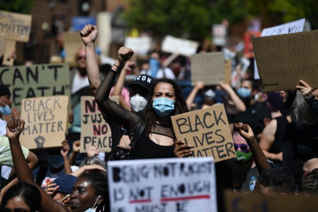 Demonstrators carry placards with slogans as they march near the US Embassy in London on M