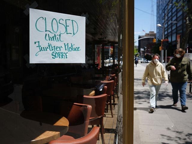 NEW YORK CITY- MAY 12: People walk through a shuttered business district in Brooklyn on May 12, 2020 in New York City. Across America, people are reeling from the loss of jobs and incomes as unemployment soars to historical levels following the COVID-19 outbreak. While some states are beginning to …
