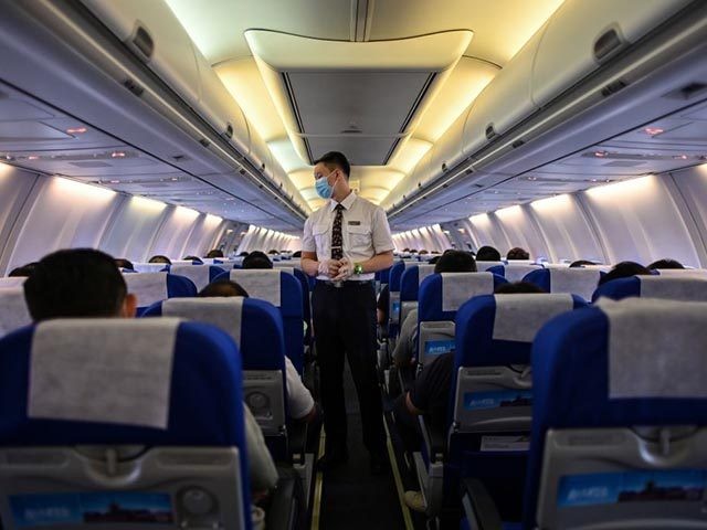 A flight attendant wearing a facemask as a preventive measure against the COVID-19 coronav