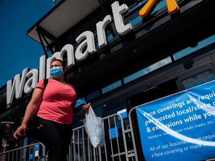 A woman wearing a facemask walks past a sign informing customers that face coverings are required in front of a Walmart store in Washington, DC on July 15, 2020. - Walmart will require shoppers to wear face masks starting next week, the US retail giant announced on July 15, joining …