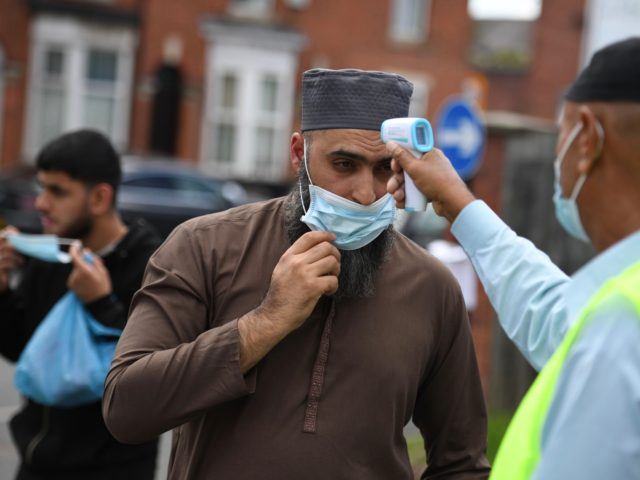 Worshippers wearing facemasks have their temperatures taken as they arrive for Friday pray