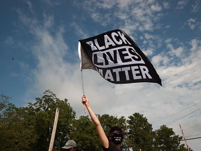 STONE MOUNTAIN, GA - AUGUST 15: A woman waves a Black Lives Matter flag during a far-right rally on August 15, 2020 near the downtown of Stone Mountain, Georgia. Georgia's Stone Mountain Park which is famous for its large rock carving of Confederate leaders planned to close on Saturday in …