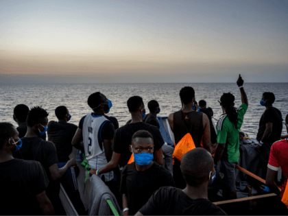 Migrants stand at sunset onboard the Sea-Watch 4 civil sea rescue ship react on sea off the coast of Sicily, Italy, on August 31, 2020. - More than 350 migrants are onboard the Sea-Watch 4, after it took more than 150 people from the German-flagged MV Louise Michel rescue vessel …