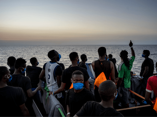 Migrants stand at sunset onboard the Sea-Watch 4 civil sea rescue ship react on sea off th