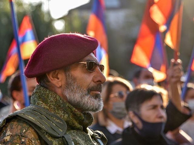 A man in lattice with a red beret protests during a rally against the country's agreement