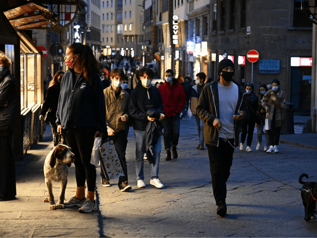 People walk at twilight across Ponte Vecchio in downtown Florence, Tuscany, on November 14, 2020 during the COVID-19 pandemic caused by the novel coronavirus. - The Italian government imposed tighter restrictions on another five regions on November 10, including Tuscany, as it tries to stem escalating new cases of coronavirus, …