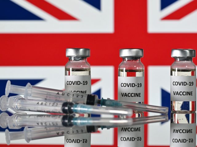An illustration picture shows vials with Covid-19 Vaccine stickers attached, and syringes, with a national flag of the United Kingdom, the Union flag, on November 17, 2020. (Photo by JUSTIN TALLIS / AFP) (Photo by JUSTIN TALLIS/AFP via Getty Images)