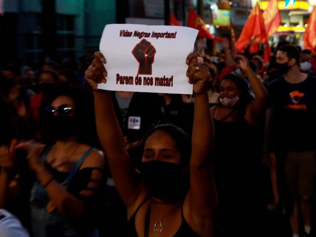 A woman holds up a sign reading Black lives matter. Stop killing us during a protest against the death of Joao Alberto Silveira Freitas in Porto Alegre, Brazil on November 23, 2020. - The death of a black man beaten by white security agents in a supermarket belonging to the …