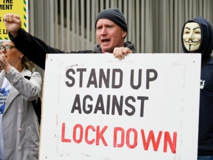EDINBURGH, SCOTLAND - SEPTEMBER 10: A protester holds a sign that reads 'stand up against lockdown' outside the Scottish Parliament entrance to demonstrate against a secondary lockdown, coronavirus face covering rules and the search for a virus on September 10, 2020 in Edinburgh, Scotland. The group, known as Saving Scotland, …