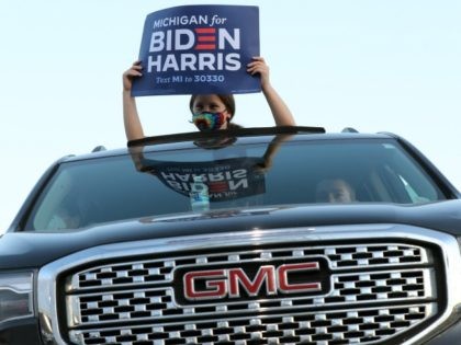 NOVI, MICHIGAN - OCTOBER 16: A supporter holds up a campaign sign during a drive-in rally