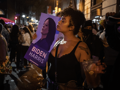 A woman holds a Biden, Harris poster after listening to the President-elect Joe Biden addr