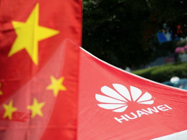 A logo of Huawei Technologies Co Ltd is seen next to a Chinese flag in Shanghai on October
