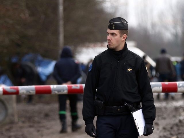 DUNKIRK, FRANCE - JANUARY 06: A police officers stands at the entrance to a new migrant camp on January 6, 2016 in Dunkirk, France. Thousands of migrants continue to live in makeshift camps in the port towns of Calais and Dunkirk in northern France, where they try and board vehicles …