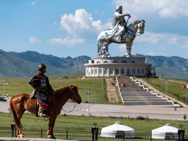 A mongolian knight stands on his horse in front of the Genghis Khan equestrian statue (the
