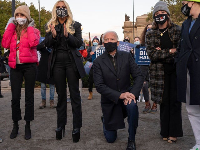 Democratic presidential candidate Joe Biden (C) kneels as he looks on with with Lady Gaga