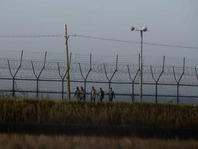 South Korean soldiers walk along a fence of the Demilitarized Zone (DMZ) separating North