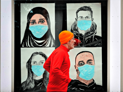 In this Nov. 16, 2020, file photo, a runner passes by a window displaying portraits of people wearing face coverings to help prevent the spread of the coronavirus in Lewiston, Maine. A deadly rise in COVID-19 infections is forcing state and local officials to adjust their blueprints for fighting a …