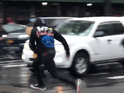 Protester flees from NYPD, nearly being struck by a car, after taunting officers. (Twitter Video Screenshot/Drew Hernandez)