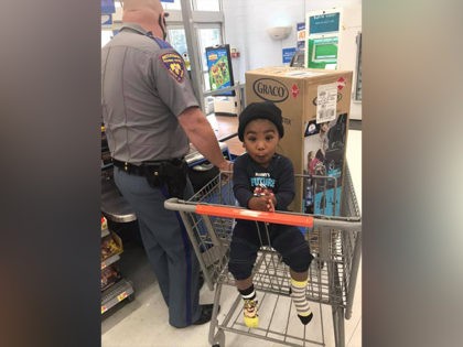 A Police officer buys a car seat for a little boy