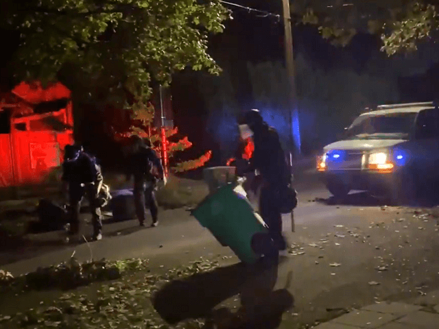 Portland police officers pick up trash cans dumped in street of residential neighborhood S