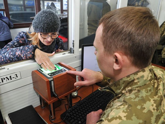 A Ukrainian border guard scans fingerprints of a Russian citizen crossing the Russian-Ukra