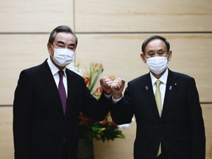 Japans Prime Minister Yoshihide Suga (R) bumps elbows with China's Foreign Minister Wang Yi (L) at the start of their meeting in Tokyo on November 25, 2020. (Photo by Behrouz MEHRI / POOL / AFP) (Photo by BEHROUZ MEHRI/POOL/AFP via Getty Images)