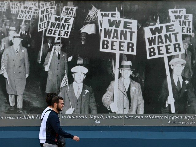A pedestrian walks past an image of a 1930s protest against prohibition depicting protestors holding "We Want Beer" placards, outside a pub in Liverpool, north west England on October 14, 2020, as new local lockdown measures come in to force to help stem a second wave of the novel coronavirus …